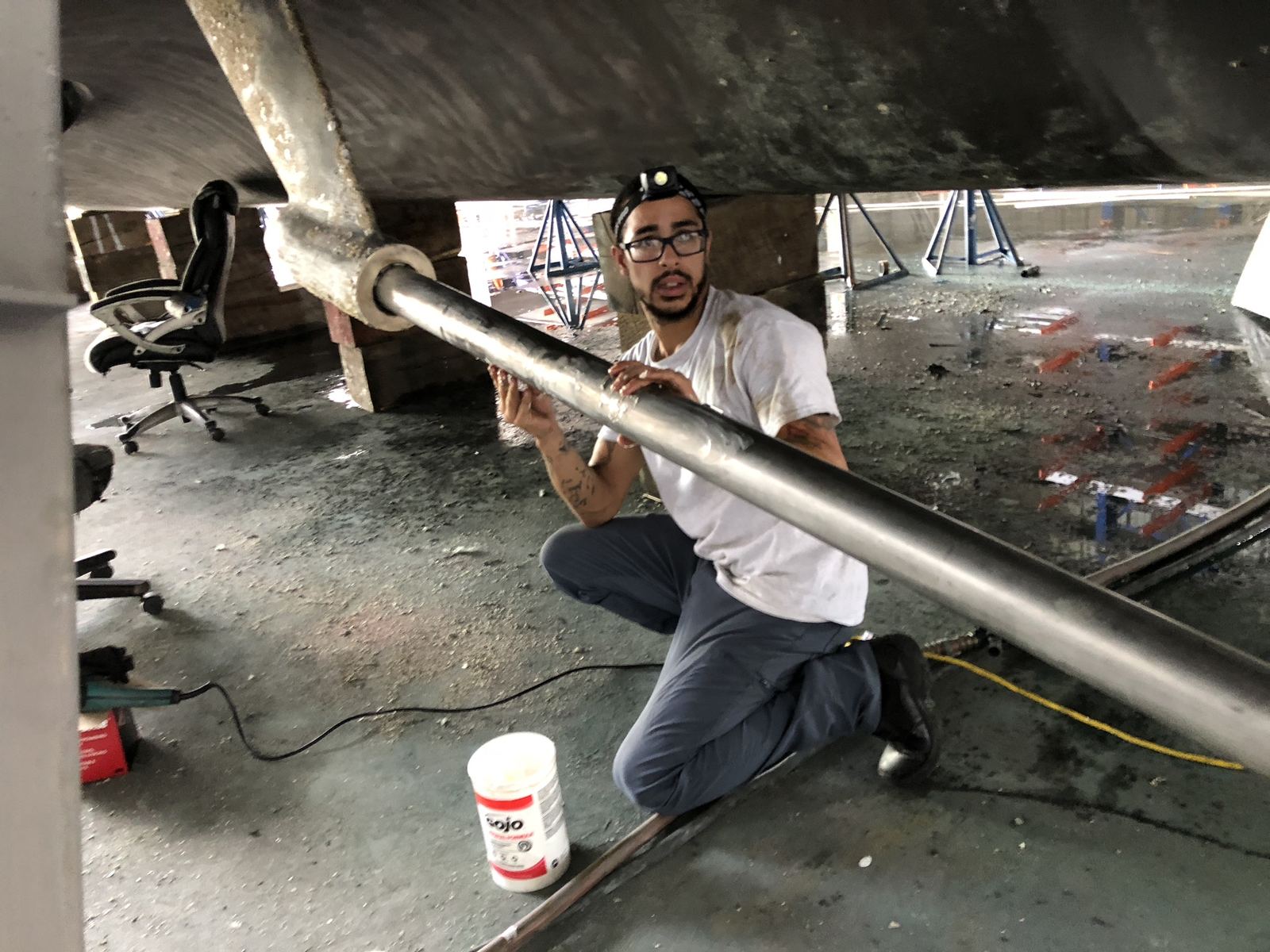 Technician inspecting a prop shaft under the hull